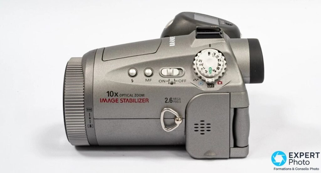 Canon PowerShot Pro90 IS, profil droit : objectif à gauche, mode dial, marquages 10x OPTICAL ZOOM IMAGE STABILIZER en rouge. 