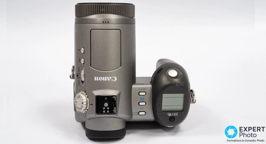 Canon PowerShot Pro90 IS, vue de dessus sur fond blanc : logo Canon, sabot externe, mode dial, ON/OFF, bouton JUMP, MF.