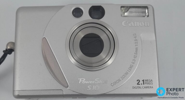 Canon PowerShot S10 vu de face, objectif Canon Zoom Lens 6.3-12.6 mm 2.8-4 fermé, flash et viseur en haut.