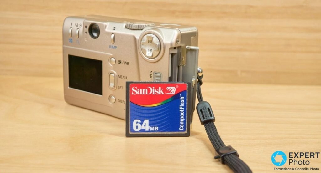 Canon PowerShot S20 et carte SanDisk CompactFlash 64 Mo posées sur planche bois clair, trappe CF du boîtier ouverte.