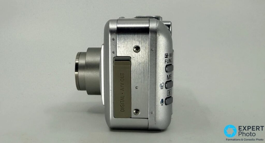 Canon PowerShot S50 de profil droit, trappe DIGITAL et A/V OUT, boutons WB FUNC, MF et icone microphone, objectif sorti.