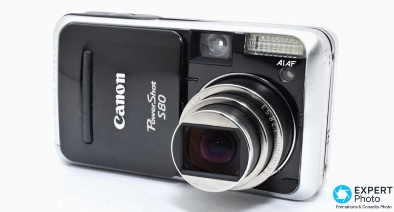 Canon PowerShot S80 vu de face en trois-quarts, capot coulissant ouvert et objectif zoom 5,8-20,7 mm déployé.