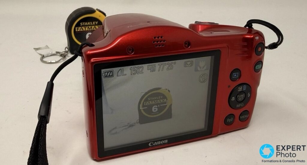Canon PowerShot SX420 IS rouge en vue arrière, écran allumé affichant un sujet en cours de cadrage avec OSD du boîtier visible