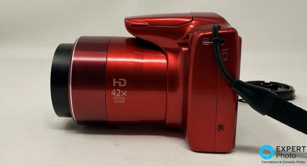 Profil gauche du Canon PowerShot SX420 IS rouge, optique déployée à fond, inscription HD 42x Optical Zoom visible sur le fût