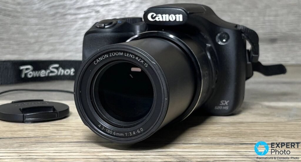 Canon PowerShot SX520 HS de trois quarts avant, objectif Canon Zoom Lens 42x IS déployé en position téléobjectif. 