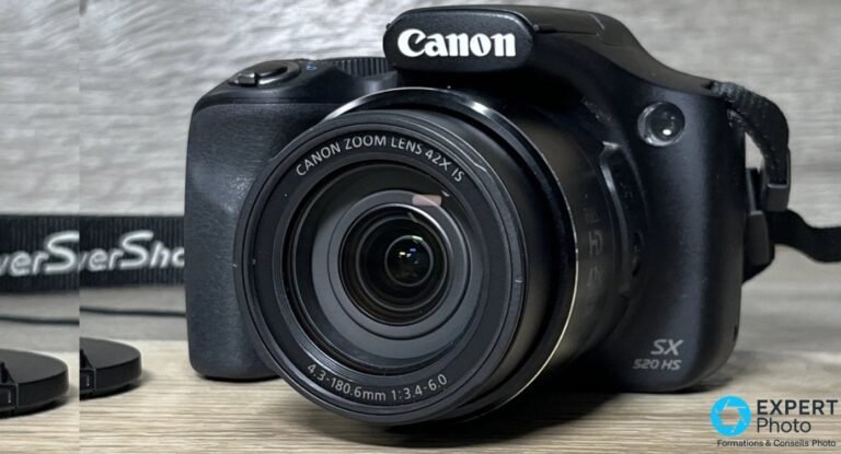Canon PowerShot SX520 HS de trois quarts avant, objectif Canon Zoom Lens 42x IS rétracté, marquage SX 520 HS visible.