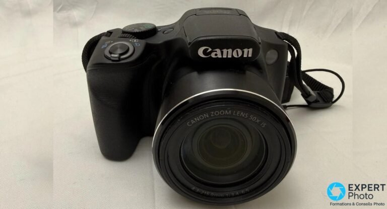 Canon PowerShot SX540 HS vu de 3/4 avant, logo Canon et marquage CANON ZOOM LENS 50X IS visibles sur l'objectif.