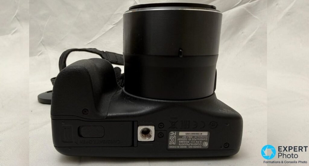 Canon PowerShot SX540 HS vu de dessous, trappe batterie fermée et marquages CANON INC. MADE IN CHINA visibles.