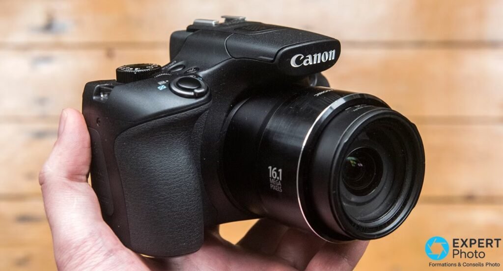 Canon PowerShot SX60 HS en prise en main, vue 3/4 avant, grip texturé et marquage 16.1 mégapixels visibles