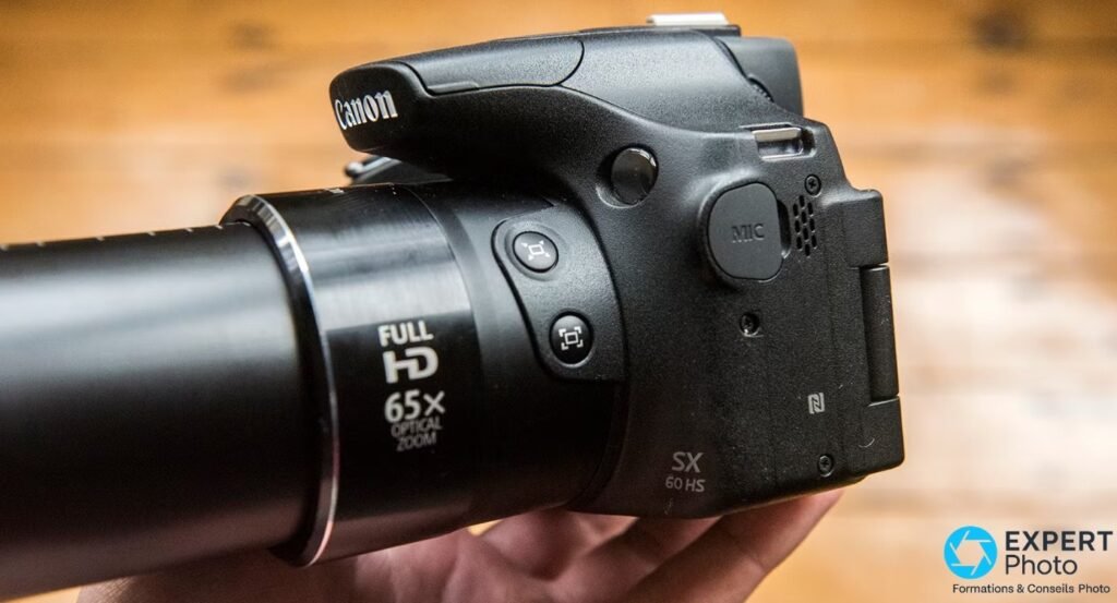 Canon PowerShot SX60 HS vu de profil gauche, zoom rétracté, marquage Full HD 65X optical zoom et grip SX 60 HS visibles 