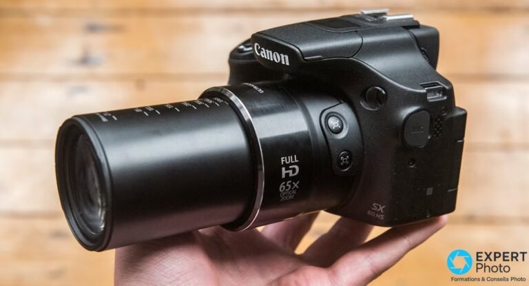 Canon PowerShot SX60 HS avec zoom optique 65x déployé tenu en main, marquage Full HD 65X optical zoom visible