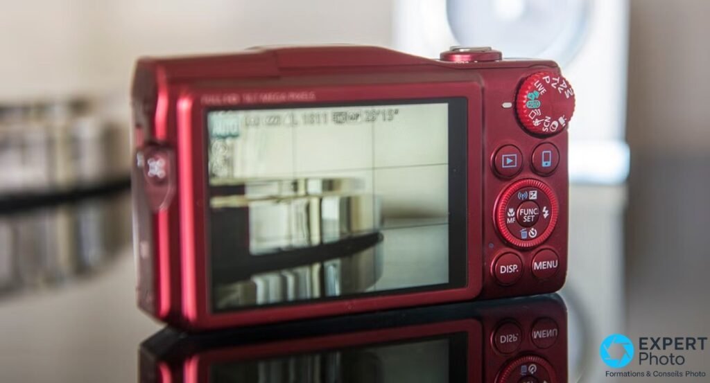 Canon PowerShot SX700 HS rouge vu de dos, écran 3 pouces allumé en mode prise de vue, molette de mode et boutons. 