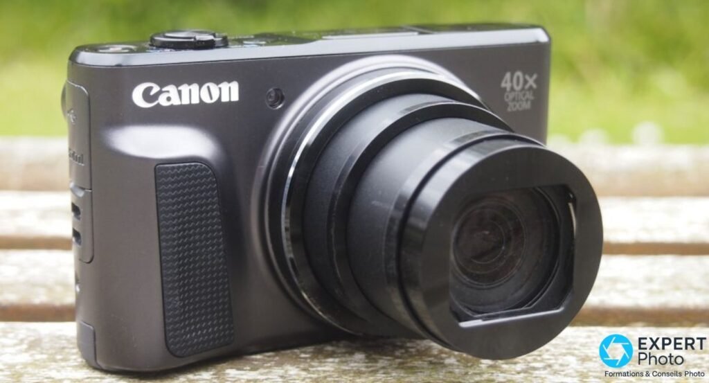 Canon PowerShot SX720 HS coloris noir avec zoom partiellement déployé posé sur banc en bois extérieur