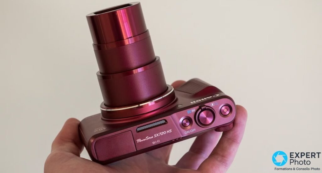 Canon PowerShot SX720 HS rouge avec zoom optique 40x complètement déployé tenu dans une main