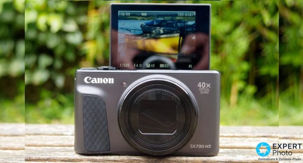 Canon PowerShot SX730 HS silver, écran arrière relevé à 180° en mode selfie, photo de bateau visible à l'écran.