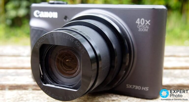 Canon PowerShot SX730 HS noir vu de face en gros plan, objectif zoom 40x déployé, marquage Canon Zoom Lens 40x IS visible.