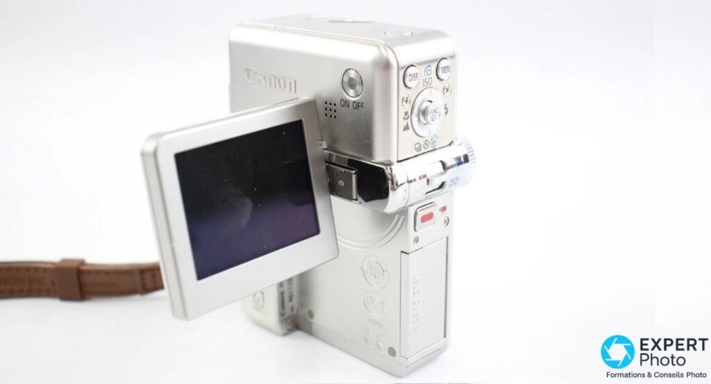 Canon PowerShot TX1 vu de l'arrière, écran orientable déployé, boutons DISP, ISO, MENU et FUNC SET visibles