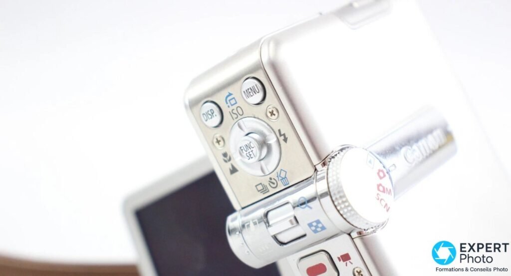 Gros plan commandes arrière du Canon PowerShot TX1 : DISP, ISO, MENU, FUNC SET et molette de modes M, SCN