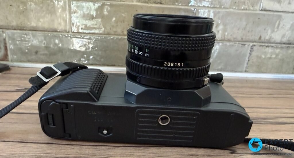 Canon T50 vu de profil avec objectif Canon FD serial 208181, semelle et pas de vis trépied 1/4 visibles