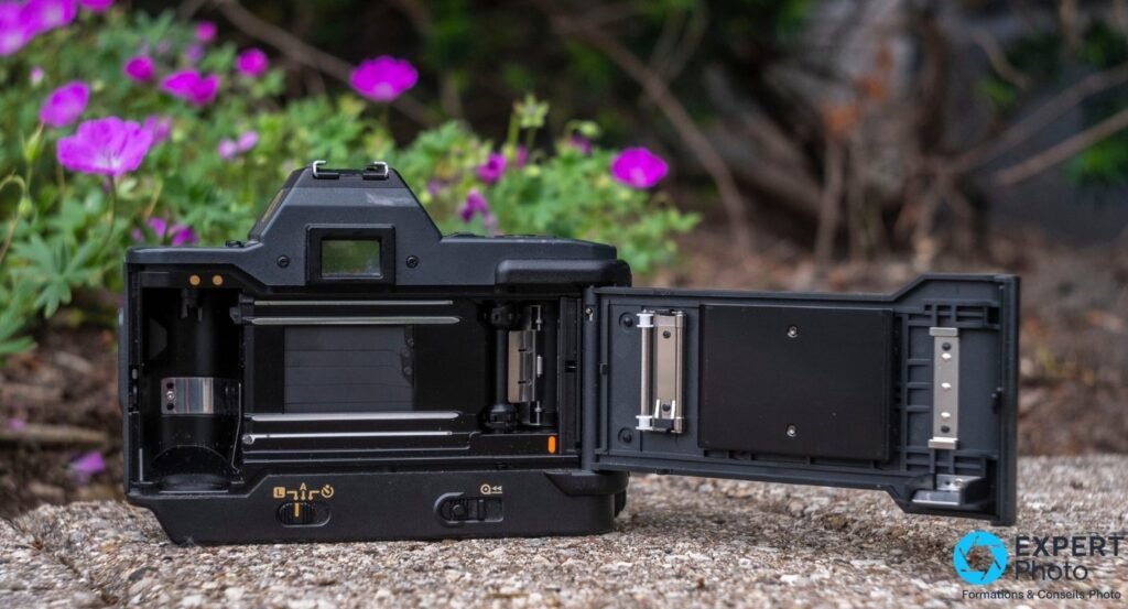 Canon T80 dos ouvert, chambre film vide visible avec rideau d'obturateur et bobine d'entraînement.