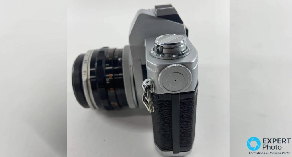 Canon TL 1968 de profil côté rembobinage, molette argentée, œillet de courroie et objectif Canon FL à gauche.