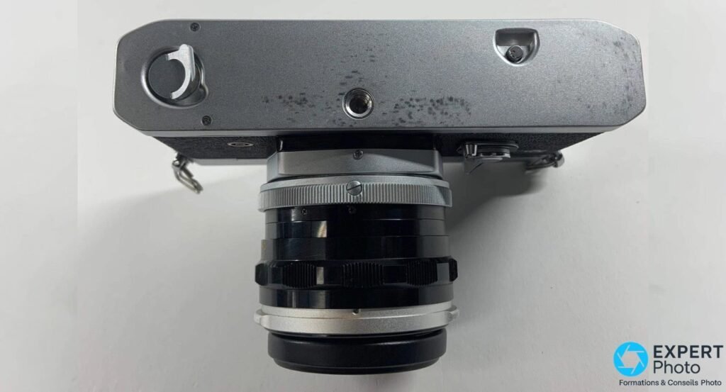 Canon TL 1968 vu de dessous, semelle métallique grise, filetage trépied central et objectif Canon FL.