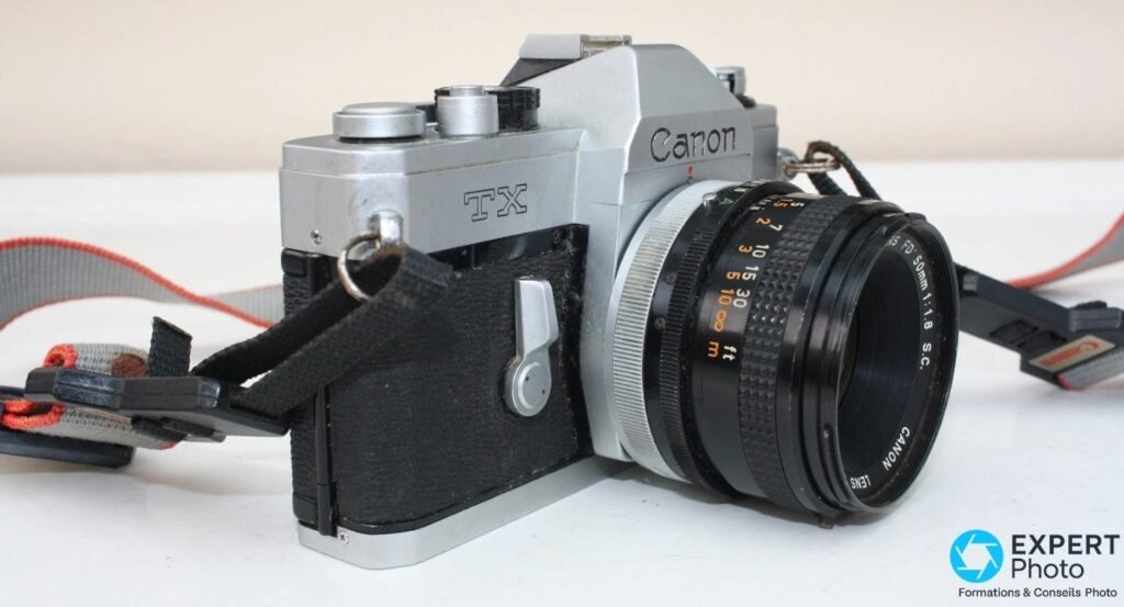 Canon TX trois-quarts avant droit, marquage TX sur le capot, objectif FD 50 mm f/1.8 S.C. avec échelle en pieds.