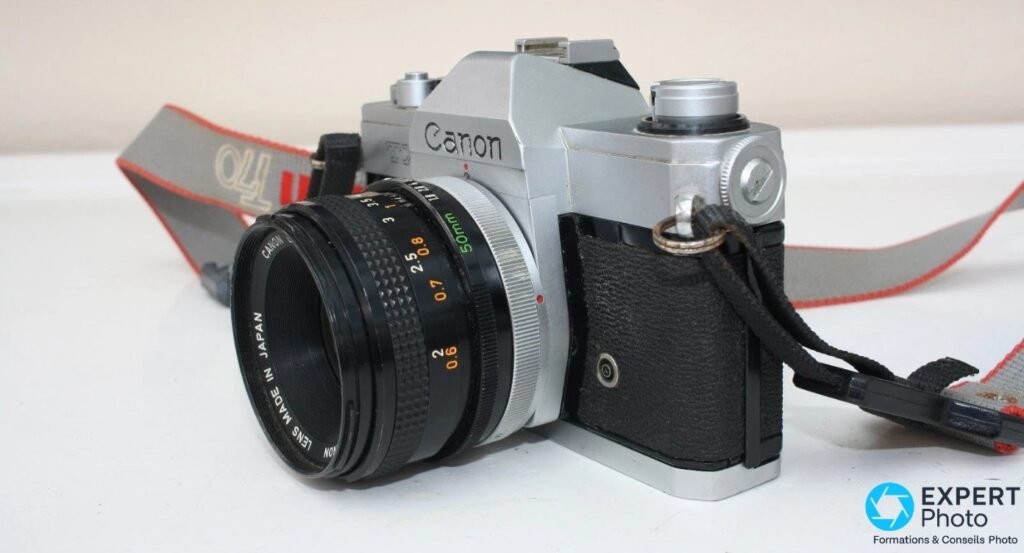 Canon TX trois-quarts avant gauche, objectif FD 50 mm avec échelle de distance et logo Canon sur le pentaprisme.
