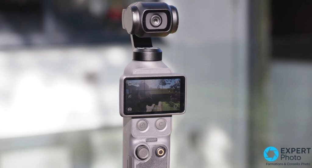  Caméra stabilisée DJI Osmo Pocket 4 coloris gris argenté, écran allumé mode Standard, deux boutons ronds et port audio visible en bas