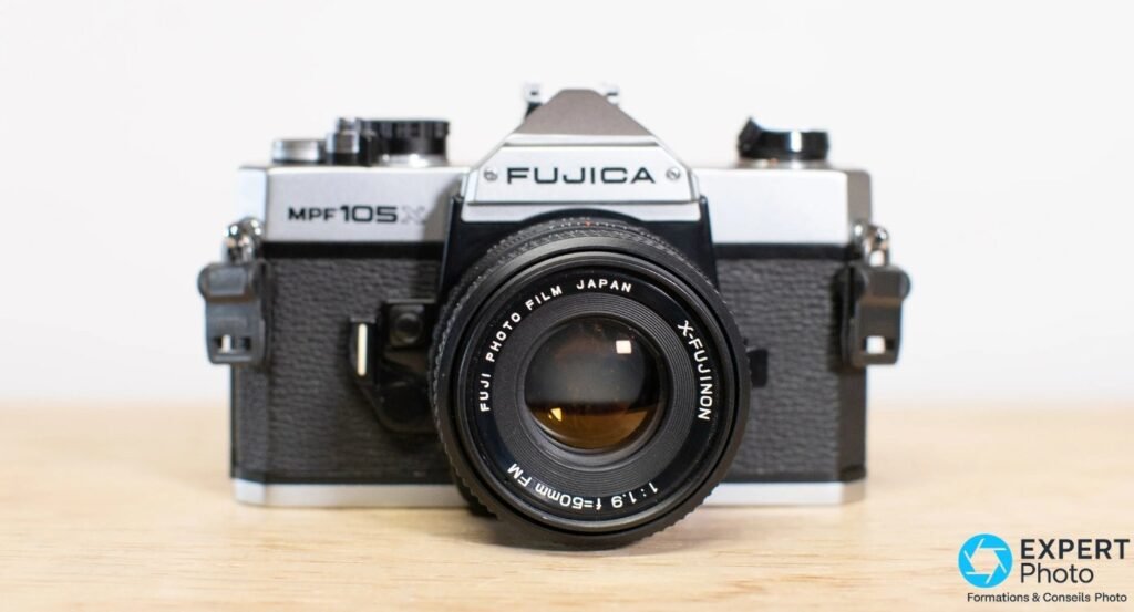 Fujica MPF 105X de face avec objectif X-Fujinon 50 mm f/1.9 monté, marquages Fuji Photo Film Japan lisibles, sur bois.