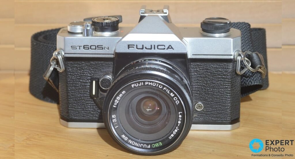 Fujica ST605N de face avec objectif EBC Fujinon-SW 28mm f/3.5, logo FUJICA et ST605N lisibles, fond bois