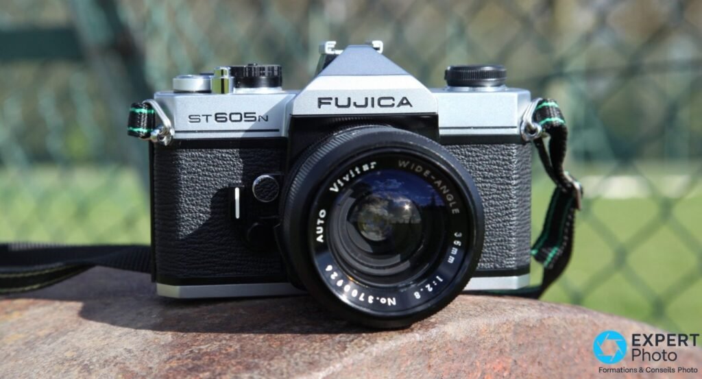 Fujica ST605N de face en exterieur avec objectif Vivitar grand-angle 35mm f/2.8 et sangle a liseres verts