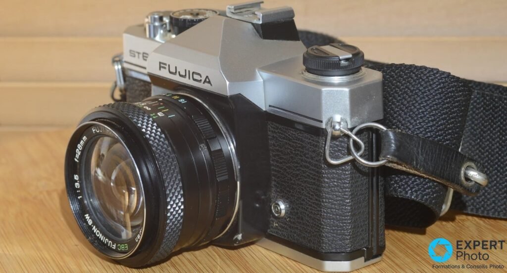 Fujica ST605N de 3/4 avant droit avec objectif EBC Fujinon-SW 28mm f/3.5, logo FUJICA visible, sur bois clair