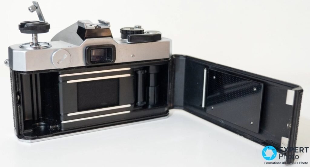  Boîtier Fujica ST605 II vu de 3/4 arrière, dos ouvert, chambre du film visible avec rideau d'obturateur en tissu. 