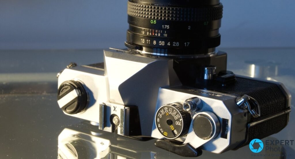 Fujica ST605 vu de dessus, barillet de vitesses gradué de B à 1/700 s, sélecteur ASA, sabot flash X et base d'objectif.