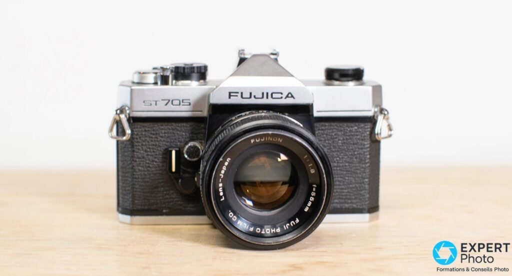 Fujica ST705 vu de face avec objectif Fujinon 55mm f/1,8, posé sur une table en bois clair.