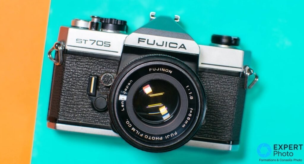 Fujica ST705 vu de dessus à plat sur fond turquoise et orange, objectif Fujinon 55mm f/1,8.