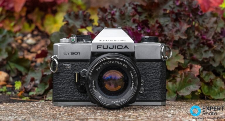 Fujica ST901 vu de face, objectif Fujinon 55 mm f/1,6 monté, fond feuillage rouge et vert