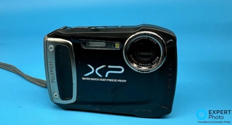 Test Fujifilm FinePix XP100 : un baroudeur 2012 face aux compacts étanches actuels Fujifilm FinePix XP100 noir vu de face, objectif Fujinon 5x rétracté, mention WATER/SHOCK/DUST/FREEZE PROOF.