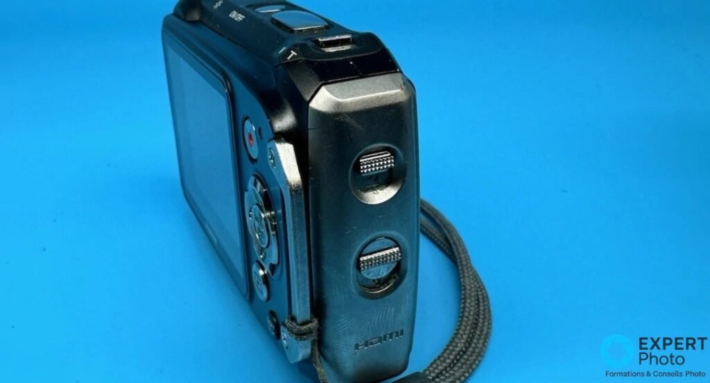 Fujifilm FinePix XP100 vu de profil, deux trappes latérales fermées et inscription HDMI gravée visibles.