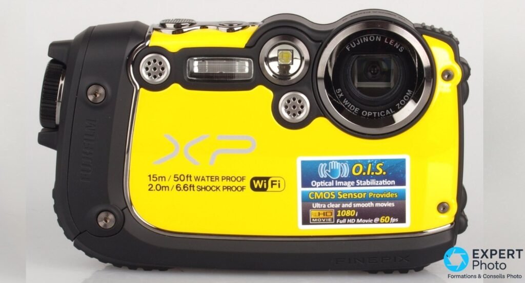 Fujifilm FinePix XP200 jaune vu de face, objectif Fujinon 5x rétracté, flash et stickers d'étanchéité visibles.
