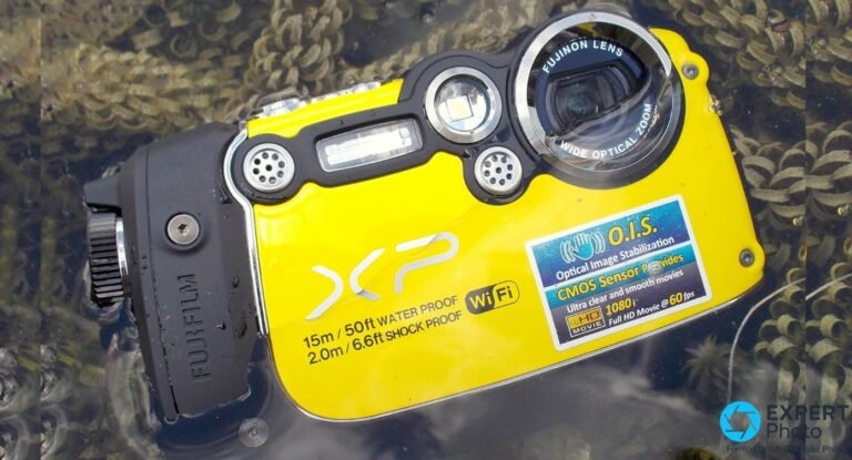 Fujifilm FinePix XP200 jaune partiellement immergé dans un plan d'eau peu profond, fond de végétation aquatique.
