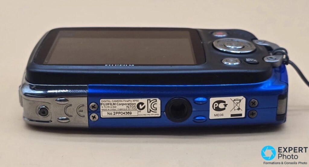 Vue arrière du Fujifilm FinePix XP50 bleu, étiquette dessous lisible DIGITAL CAMERA FinePix XP50 et FUJIFILM Corporation.