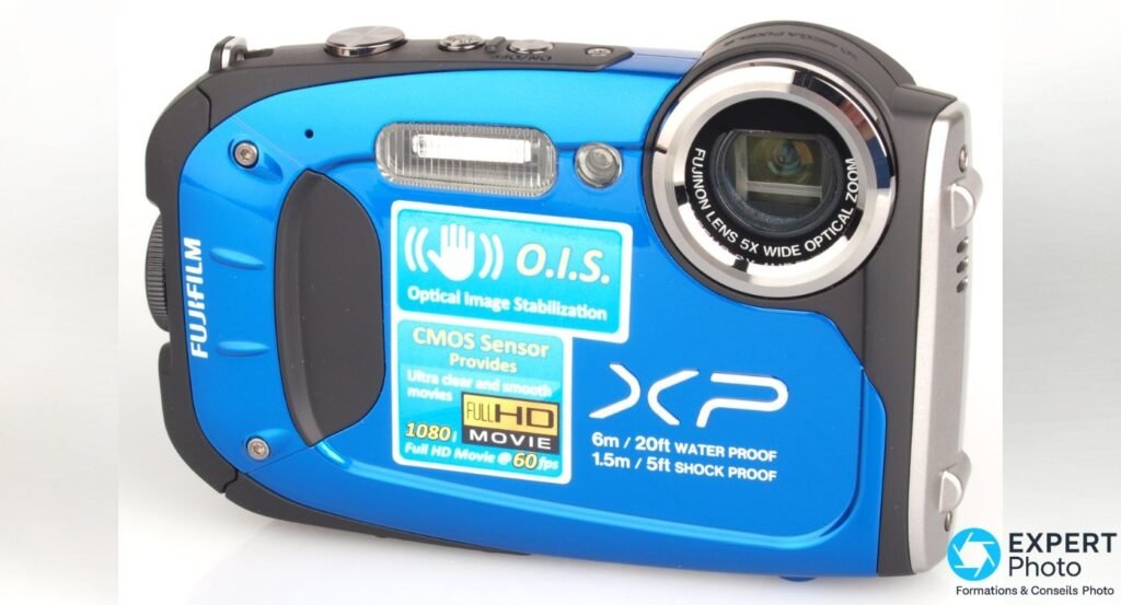 Fujifilm FinePix XP60 bleu vu de face, objectif Fujinon 5x déployé, stickers étanchéité 6 m et antichoc 1,5 m visibles.