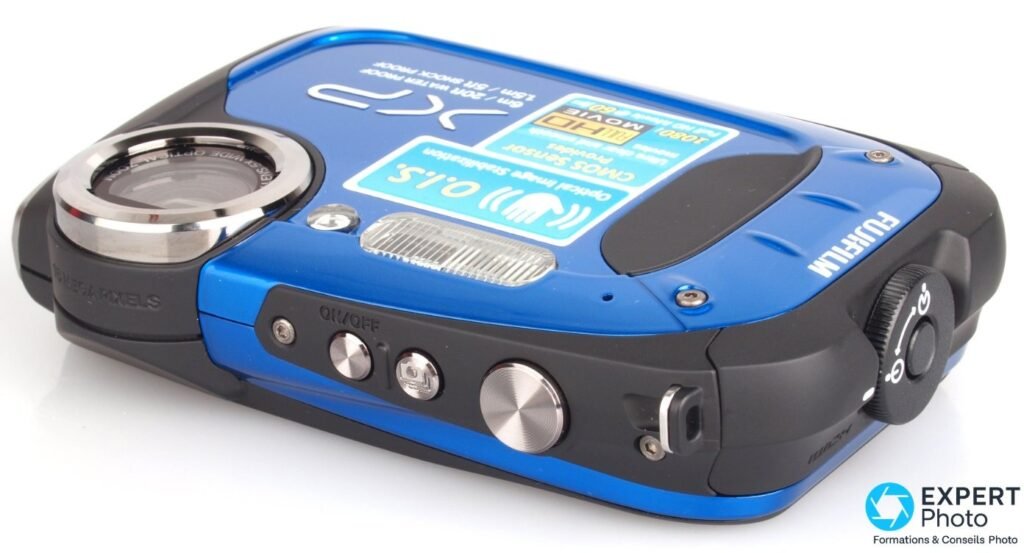Fujifilm FinePix XP60 bleu vu en plongée trois-quarts, top-deck avec déclencheur, bouton ON/OFF et molette de modes visibles.