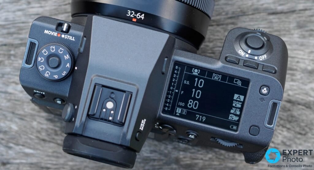 Capot superieur du Fujifilm GFX100 II, molette de modes P/A/S/M, griffe et ecran de controle