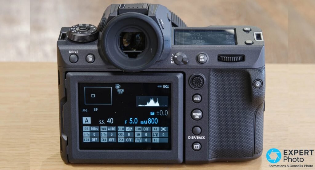 Face arriere du Fujifilm GFX100 II, ecran LCD allume avec histogramme et reglages, viseur 