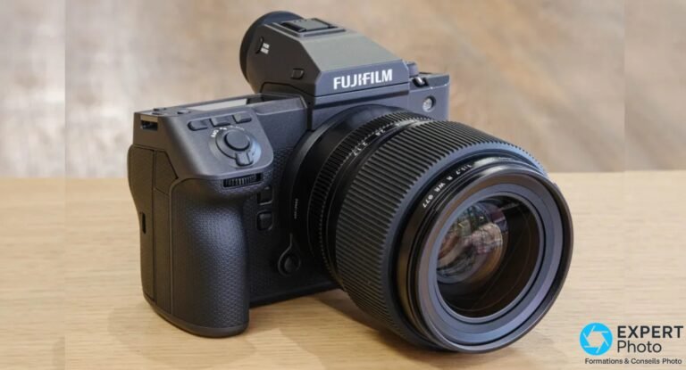 Fujifilm GFX100 II de trois quarts avant, objectif GF 55 mm monté, sur plan en bois clair