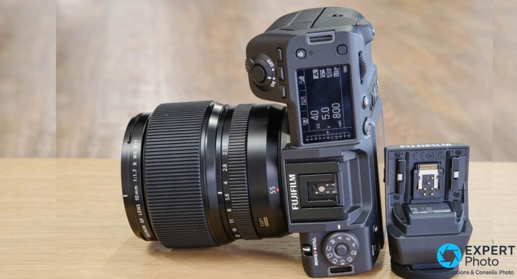  Fujifilm GFX100 II de dessus, molette MOVIE/STILL, écran d'épaule allumé et objectif GF 55 mm