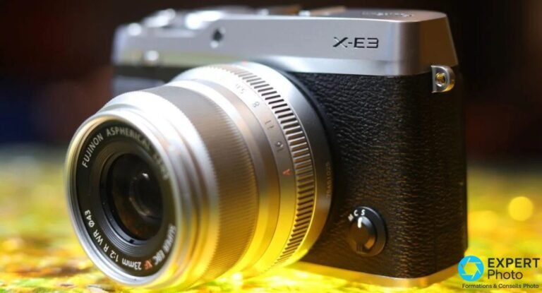 Boîtier Fujifilm X-E3 silver et noir avec objectif Fujinon XF 23mm f/2 R WR silver, vue 3/4 avant sur fond bokeh doré.